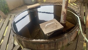 A wooden barrel with a metal structure inside, a wooden bench, and a metal pole.
