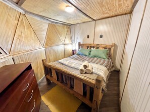 A bedroom with a wooden bed, a nightstand, a dresser, and a yellow rug.