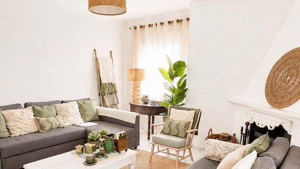 Ein Wohnzimmer mit grauem Sofa, einem weißen Couchtisch, einem Holznachttisch und einer Pendelleuchte.