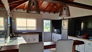 Una cocina moderna con armarios blancos, una isla de madera e iluminación colgante.