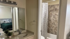 Ein Badezimmer mit Waschbecken, Spiegel, Toilette und Duschvorhang.