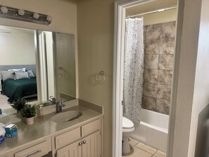 Une salle de bain équipée d’un lavabo, d’un miroir, de toilettes et d’un rideau de douche.