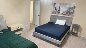 Ein Schlafzimmer mit Bett, Nachttisch, Kommode, Tür und Deckenventilator.