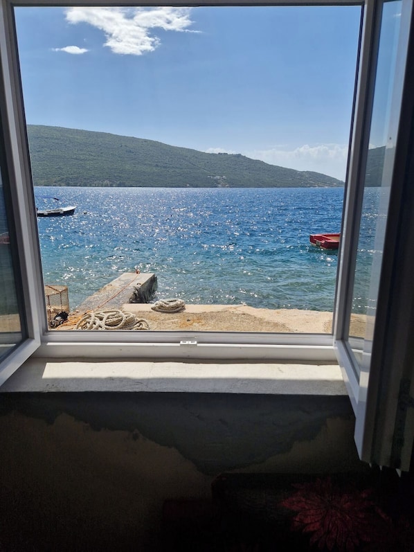 A view through a window of a lake with boats, a dock, and a hill in the background.