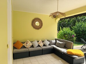A sectional sofa with patterned cushions, a woven wall hanging, and a hanging light fixture. - Villa Solana, private pool with tropical garden in Sainte-Luce (Sainte-Luce)