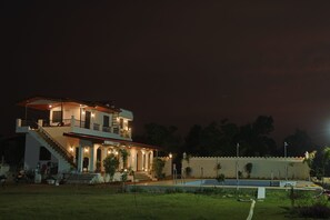 A two-story house with a balcony, a staircase, and a swimming pool.