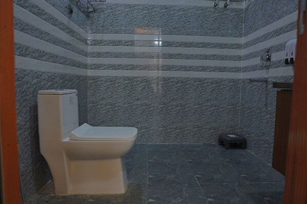 A bathroom with a toilet, a shower, and a small bench.