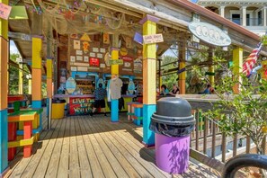 Un espacio exterior colorido con una terraza de madera, un bote de basura y un letrero que dice "Live the Fun You Live".