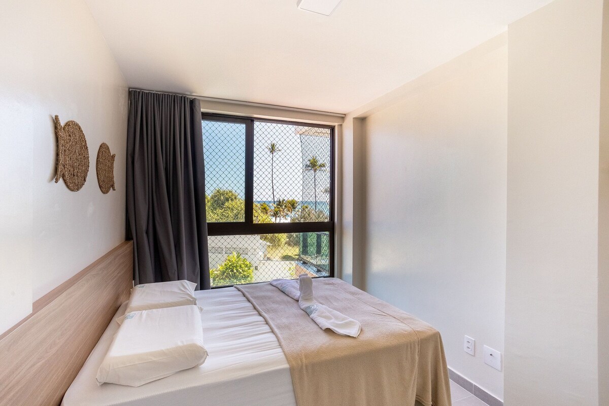 Ein Hotelzimmer mit Bett, Fenster mit Blick und zwei Wandbildern.