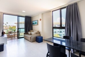 Ein modernes Wohnzimmer mit Sofa, Esstisch und einem Balkon mit Aussicht.