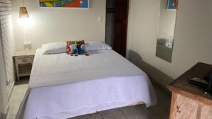 Et soveværelse med seng, et natbord, en lampe, et maleri, et spejl og en trækommode.