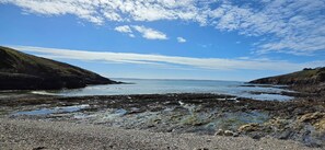 Une côte rocheuse bordée d’une eau calme et surplombée d’un ciel dégagé.