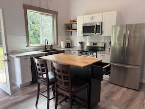 A modern kitchen with a wooden island, stainless steel appliances, and white cabinetry.