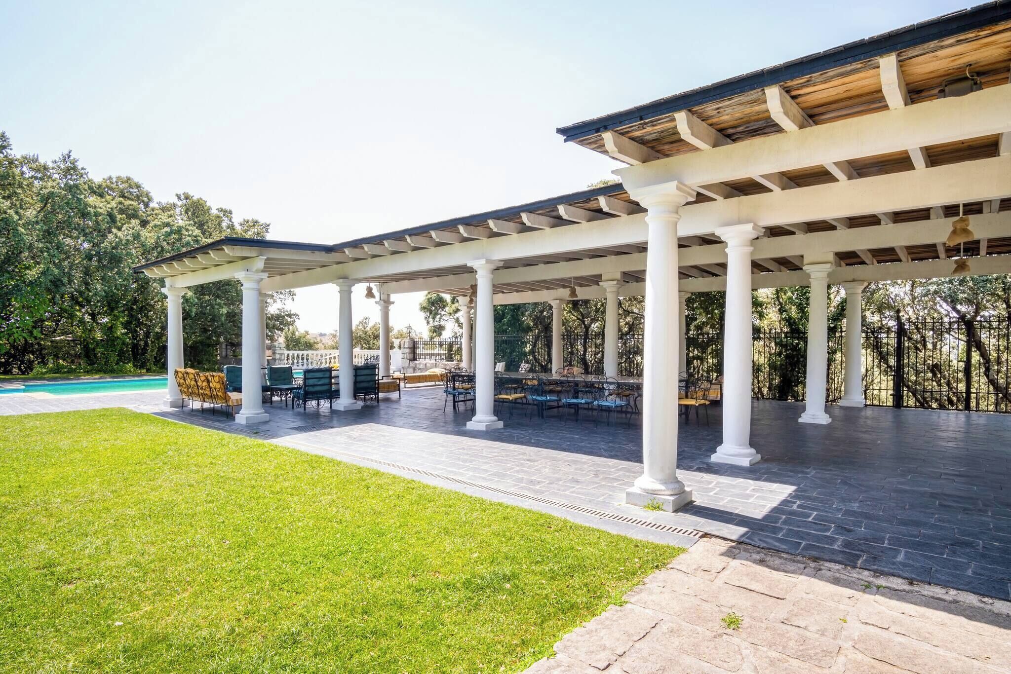 Un pati exterior cobert amb piscina, zones d'estar i un jardí ben cuidat.