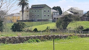 Uma área residencial com um muro de pedra, um campo verde e casas com muitas janelas.