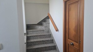 Uma escadaria com corrimão de madeira que leva a uma porta de madeira.