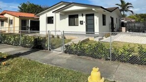A single-story house with a white exterior, a black door, and a small front yard. - Miami International Airport Stay/beautiful home in central location (Miami)