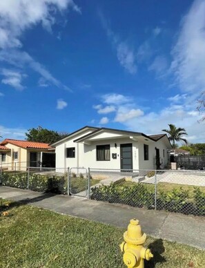 A single-story house with a white exterior, a black door, and a small front yard. - Miami International Airport Stay/beautiful home in central location (Miami)