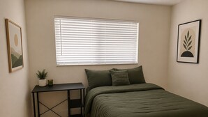 A bedroom with a bed, a desk, a window with blinds, a small plant, and a picture on the wall. - Miami International Airport Stay/beautiful home in central location (Miami)