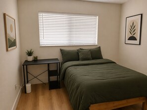 A bedroom with a bed, a desk, a window with blinds, a small plant, and a picture on the wall. - Miami International Airport Stay/beautiful home in central location (Miami)