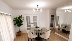 A dining area with a round glass table, four chairs, a potted plant, and a mirror reflecting the room. - Miami International Airport Stay/beautiful home in central location (Miami)