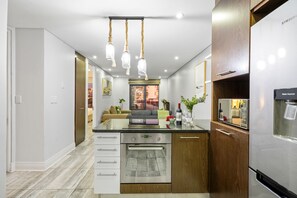 A modern kitchen with a central island, built-in oven, and stainless steel refrigerator. - Eden On The Bay 231 - Two Bedroom Apartment, Sleeps 4 (Cape Town)