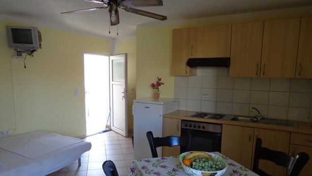 Una cucina compatta con tavolo e sedie, una ventola a soffitto e un piccolo frigorifero.