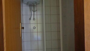 Un bagno con un WC, una doccia con parete piastrellata e una porta con maniglia.
