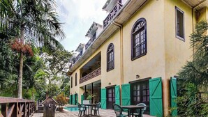 Un edificio con una terrazza in legno, posti a sedere all'aperto e una piscina.