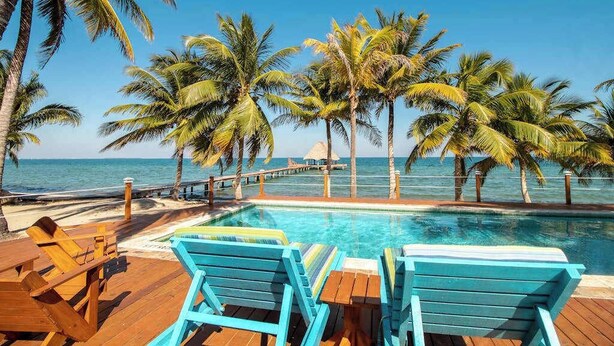 Ein Poolbereich mit Holzliegen und freiem Blick auf das Meer.
