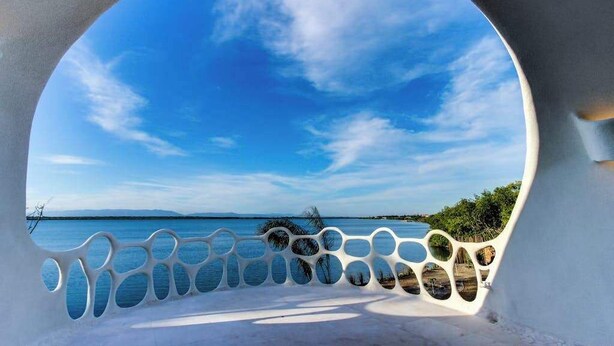 Un élément architectural circulaire offrant une vue sur une mer calme et un ciel dégagé.