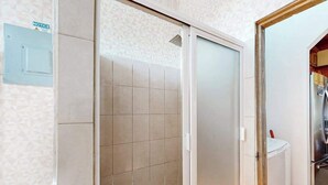 Une salle de bain équipée d’une douche, de toilettes et d’un panneau d’information accroché au mur.