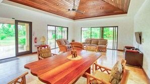 Un salón amplio con techo de madera, ventanas grandes y asientos cómodos.
