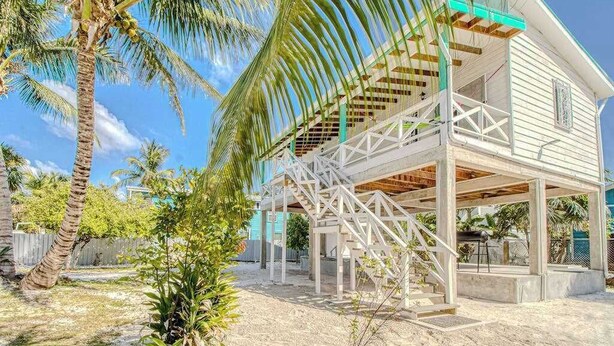 Una casa costera con terraza de madera, una escalera y vista despejada al océano.