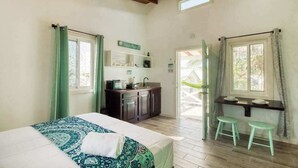Un dormitorio con cama, kitchenette y zona de comedor con taburetes.