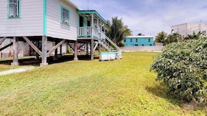 A two-story house with a porch, a staircase, and a small shed. - Colorful studio cabana with WiFi, partial AC, yard & picnic area - walk to town (Caye Caulker)