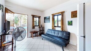 Una sala de estar con sofá, televisor, ventilador y mesa.