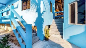 Un edificio azul con una escalera, una ventana y una planta.