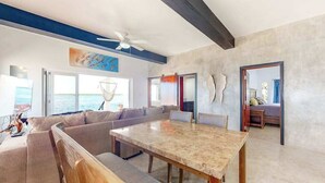 A modern living room with a large sectional sofa, a dining table, and a view of the ocean. - Waterfront home in a quiet area with amazing views, pool, lanai & hammock (San Pedro)