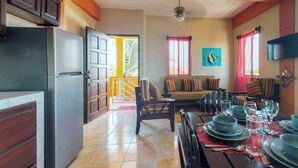A modern kitchen with a dining area, a sofa, and a TV mounted on the wall. - Inviting apartment w WiFi & partial AC - steps from the ocean, walk everywhere (San Pedro)