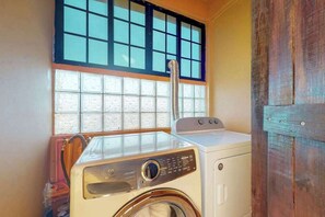 Een wasserette met een wasmachine, een droger en een raam met jaloezieën.