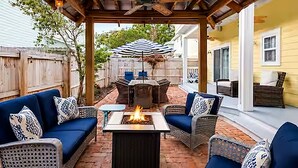 An outdoor patio with a fire pit, wicker furniture, and a ceiling fan.
