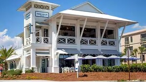 A white building with a sign reading 'TRINITY GALLERY' and a covered outdoor seating area with umbrellas.