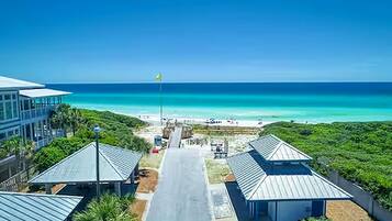 A coastal hotel with a clear view of the ocean, a flag, and a pathway leading to the beach.