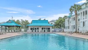 A swimming pool with lounge chairs, a building with a green roof, and a palm tree.