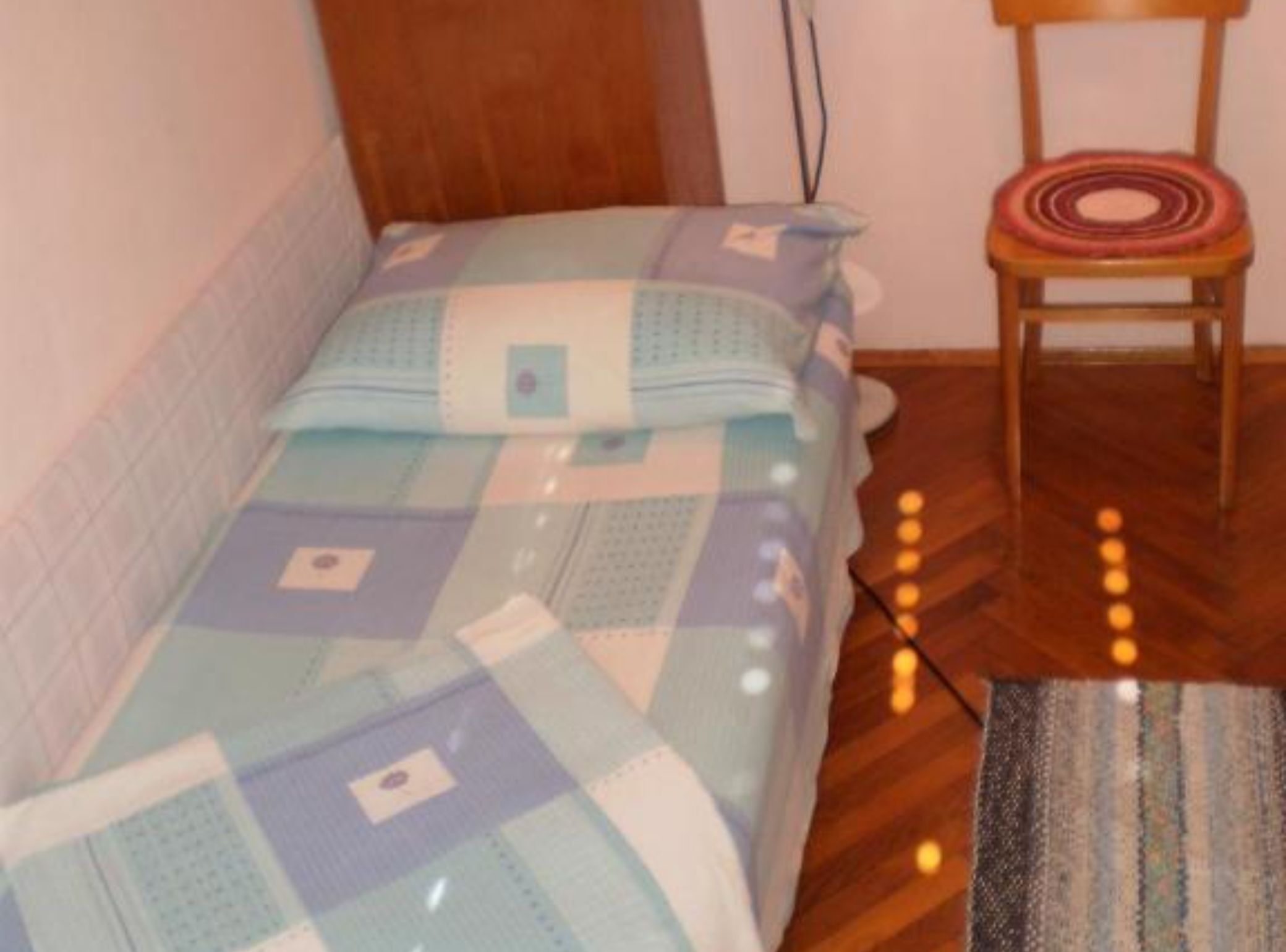 Un dormitorio pequeño con cama, una silla y una alfombra.