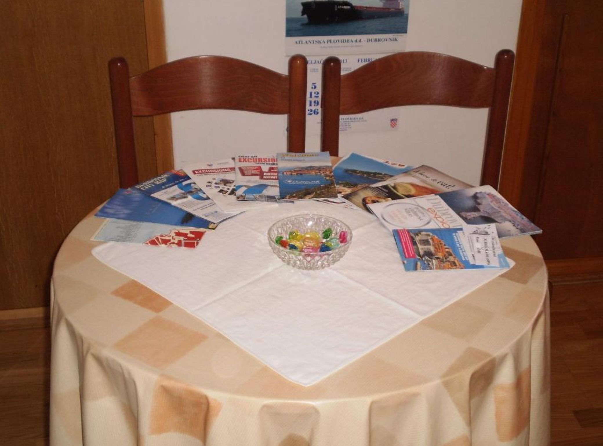 Ein Tisch mit Broschüren, einer Schale Süßigkeiten und einem Stuhl.