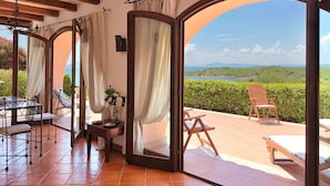 A room with a view of the sea, a wooden ceiling, and a table with chairs. - Il Delfino - Seaside Bliss (Golfo Aranci)