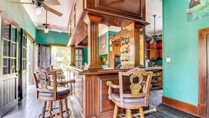 A bar area with wooden chairs and a bar counter. - Deluxe Studio with Riverfront Location, WiFi, AC, & Pool (San Ignacio)
