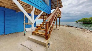 A wooden staircase leading to a blue building with a view of the sea.